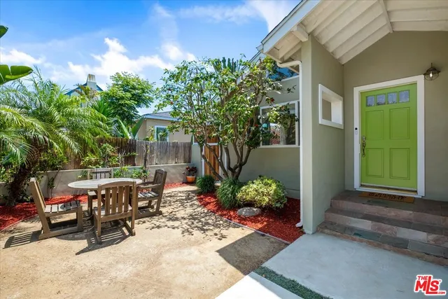 a view of a patio with table and chairs potted plants and floor to ceiling window