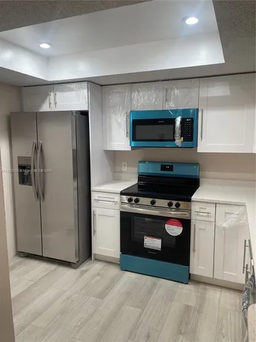 a kitchen with white cabinets and appliances