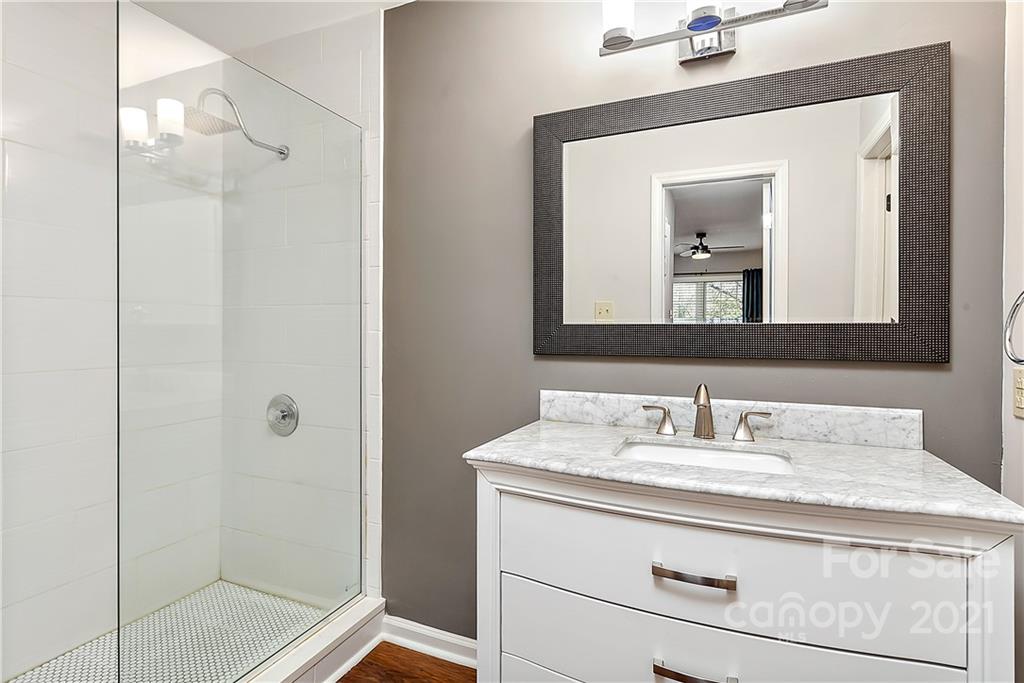 5011 Sharon Road, Unit E Charlotte, NC 28210 - Photo 12 of 19 a bathroom with a granite countertop sink a mirror and shower