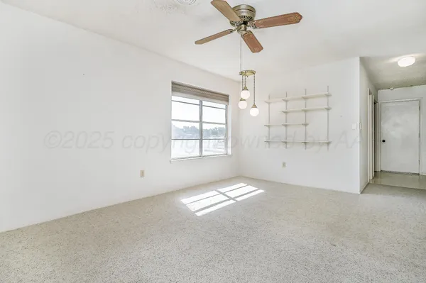 an empty room with windows and fan chandelier fan