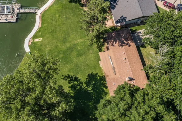 an aerial view of a residential houses with outdoor space and trees all around