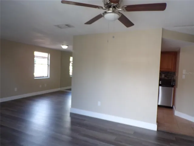 a view of an empty room with wooden floor and a window