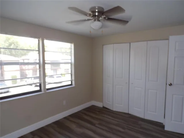 a view of an empty room with a window and wooden floor