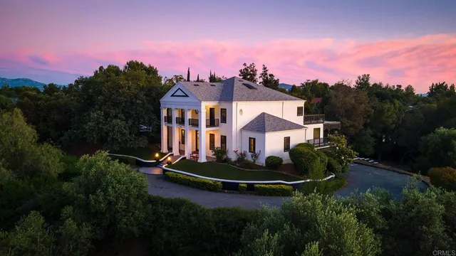 a front view of a house with a garden and trees