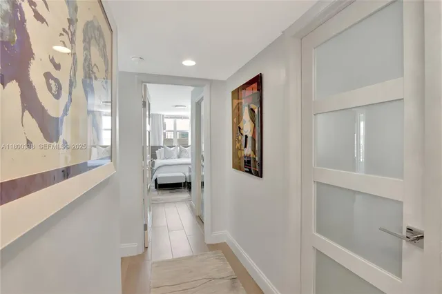a view of a hallway with wooden floor and a bathroom