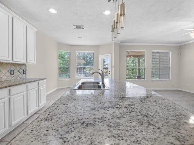 a view of a kitchen with granite countertop a large window cabinets and stainless steel appliances