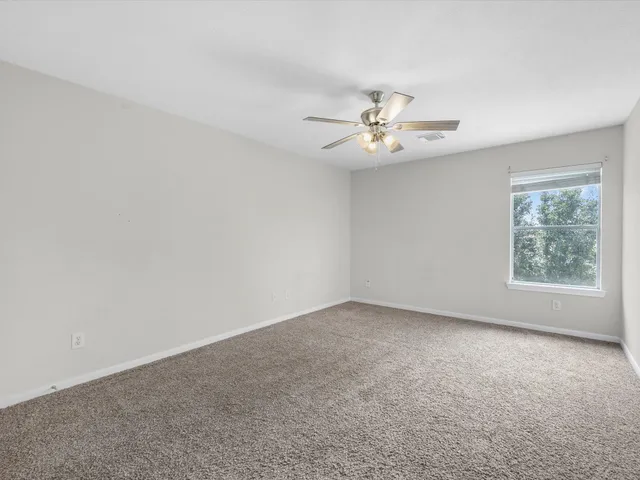an empty room with a window and a chandelier fan