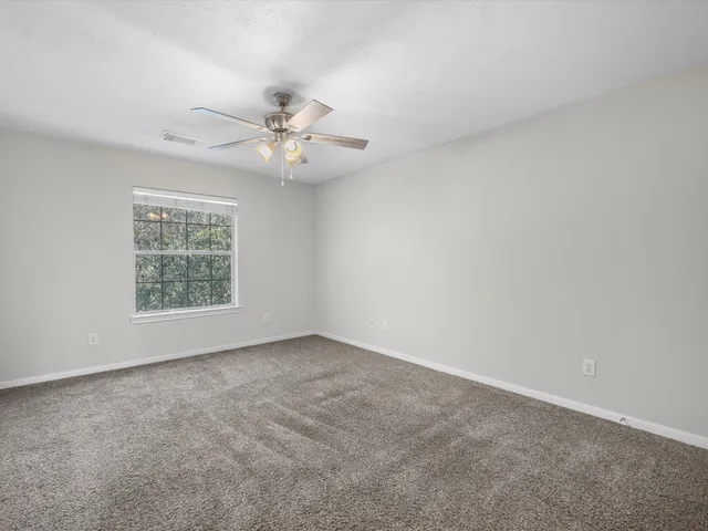 an empty room with a window and a ceiling fan