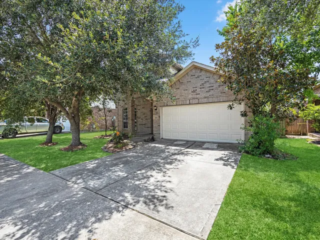 a front view of a house with a yard and tree s