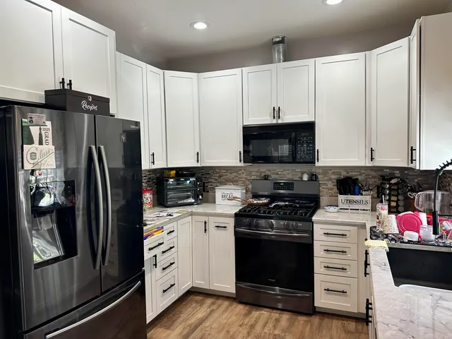 a kitchen with a refrigerator stove and white cabinets