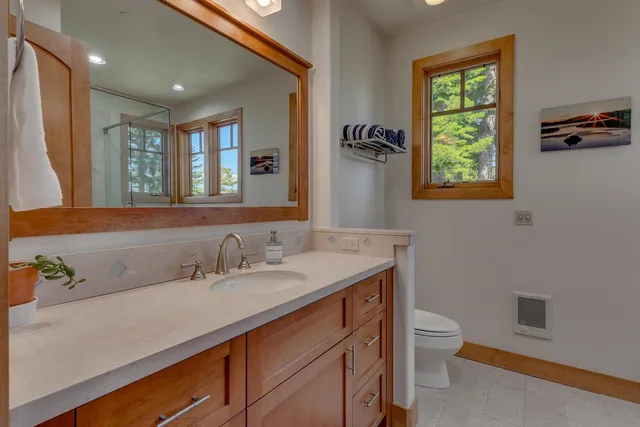 a bathroom with a granite countertop sink a large mirror a toilet and a window