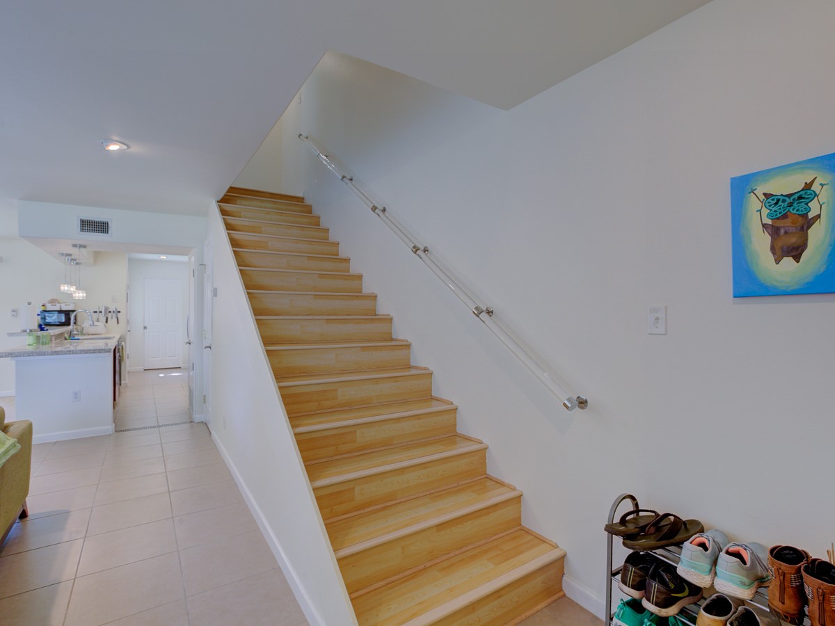 710 Castle Ridge Road, Unit B Austin, TX 78746 - Photo 15 of 27 Luminous wooden stairs ascend gracefully, contrasting with the smooth tile flooring below.