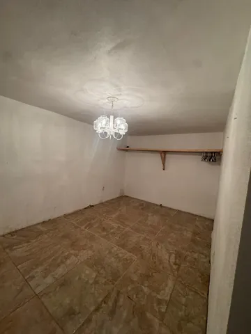 an empty room with a chandelier fan and windows
