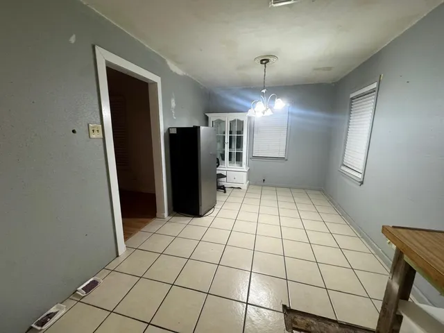 a view of a refrigerator in kitchen and an empty room