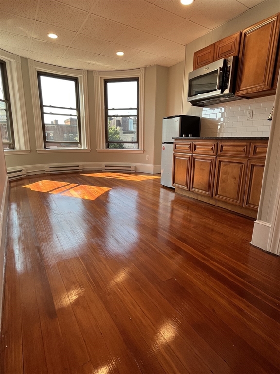a living room with stainless steel appliances wooden floors and a fireplace