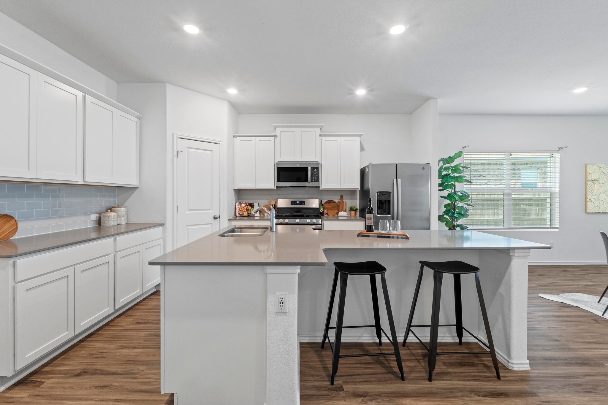 1705 Woolsey Way Leander, TX 78641 - Photo 14 of 35 a kitchen with stainless steel appliances granite countertop a stove top oven a sink dishwasher and white cabinets with wooden floor