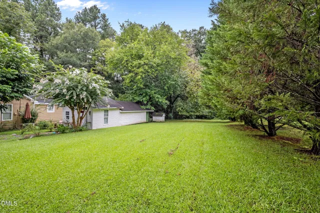 a view of a large trees with barn in the background