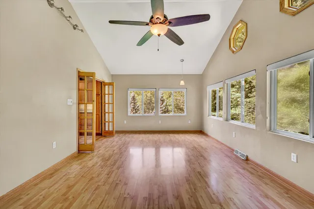 a view of an empty room with a window and wooden floor