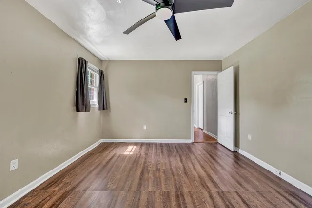 a view of empty room with wooden floor and ceiling fan