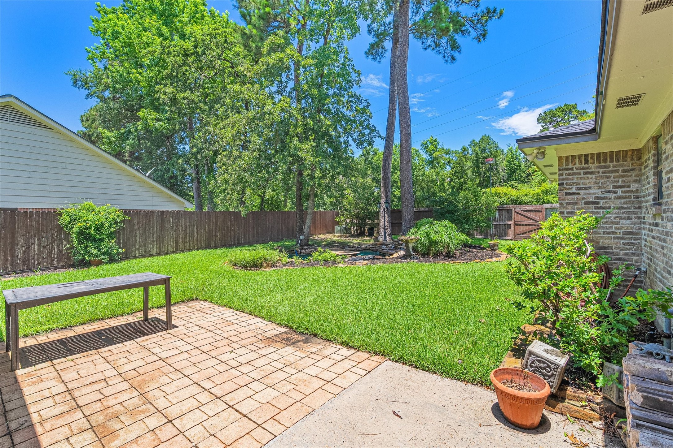 826 North Rivershire Drive Conroe, TX 77304 - Photo 33 of 46 The fully fenced backyard opens up with lush green lawn, mature trees providing natural shade, and brick paver patio space ready for weekend gatherings. There is genuine room to breathe out here.