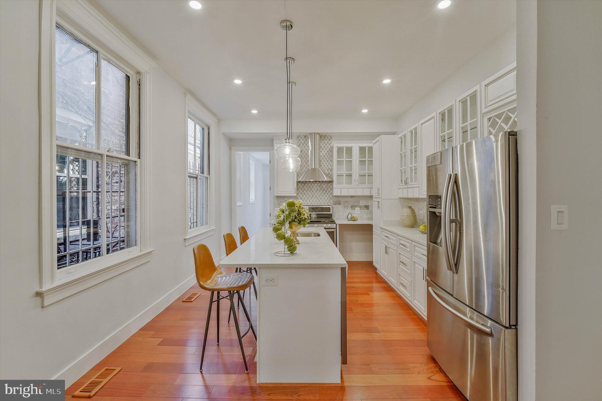 1240 Columbia Road Northwest, Unit 1 Washington, DC 20009 - Photo 4 of 25 a kitchen with stainless steel appliances granite countertop a refrigerator a oven a sink and a dining table with wooden floor