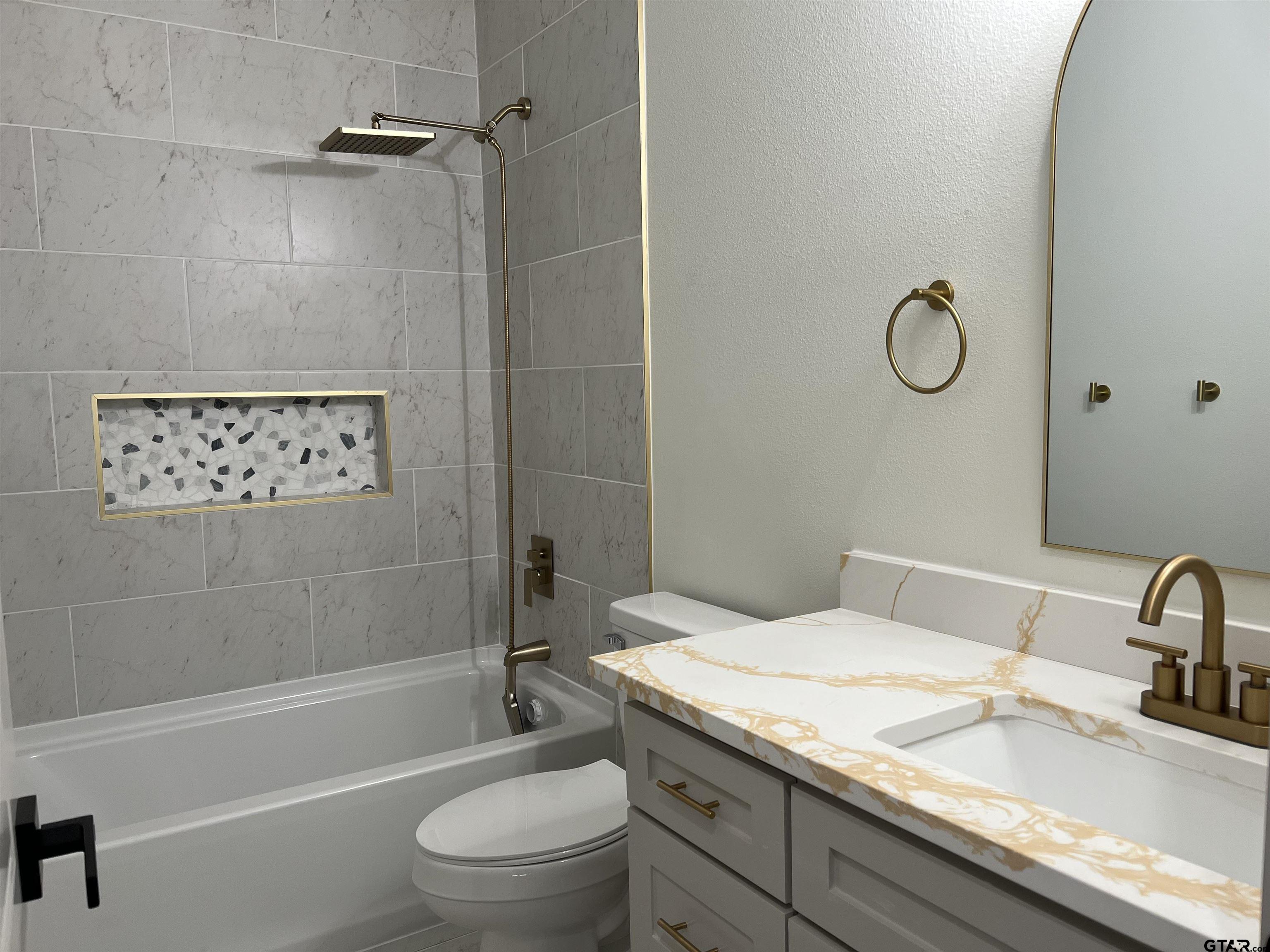 a bathroom with a granite countertop toilet a sink and bathtub