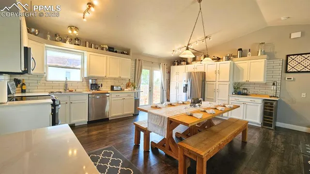 a kitchen with a table chairs stove a sink dishwasher and cabinets with wooden floor