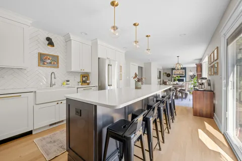 a kitchen with kitchen island a table chairs sink and cabinets