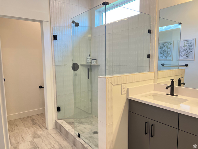 1951 2900 West Provo, UT 84601 - Photo 14 of 21 Bathroom featuring a walk-in shower with clear glass enclosure and black fixtures, a built-in shower shelf, a vanity with a white countertop and rectangular sink, a matte black faucet, and grey cabinetry with black hardware