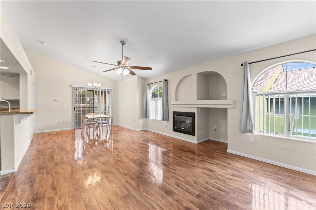 7950 West Flamingo Road, Unit 2142 Las Vegas, NV 89147 - Photo 6 of 24 Natural light illuminates the open-concept living and dining area, featuring sleek wood flooring and a modern fireplace.