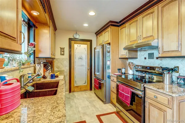 a kitchen with stainless steel appliances granite countertop a stove a sink and a refrigerator