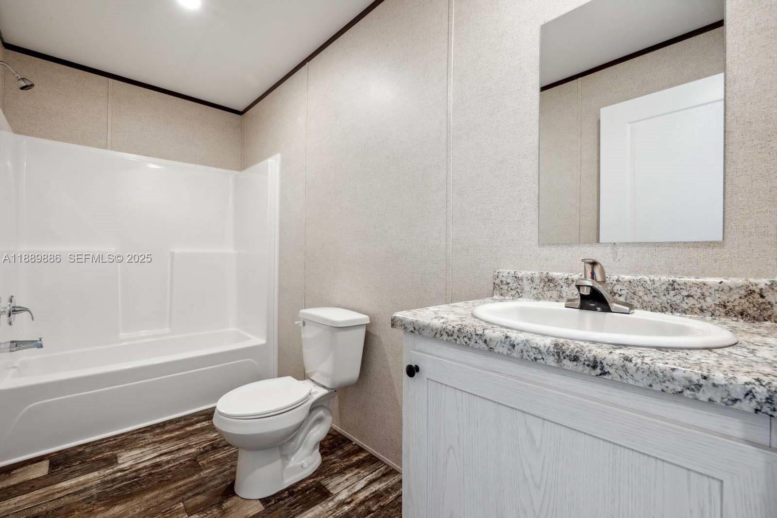 357 Horse Club Avenue Clewiston, FL 33440 - Photo 8 of 15 a bathroom with a granite countertop toilet a sink and a bathtub