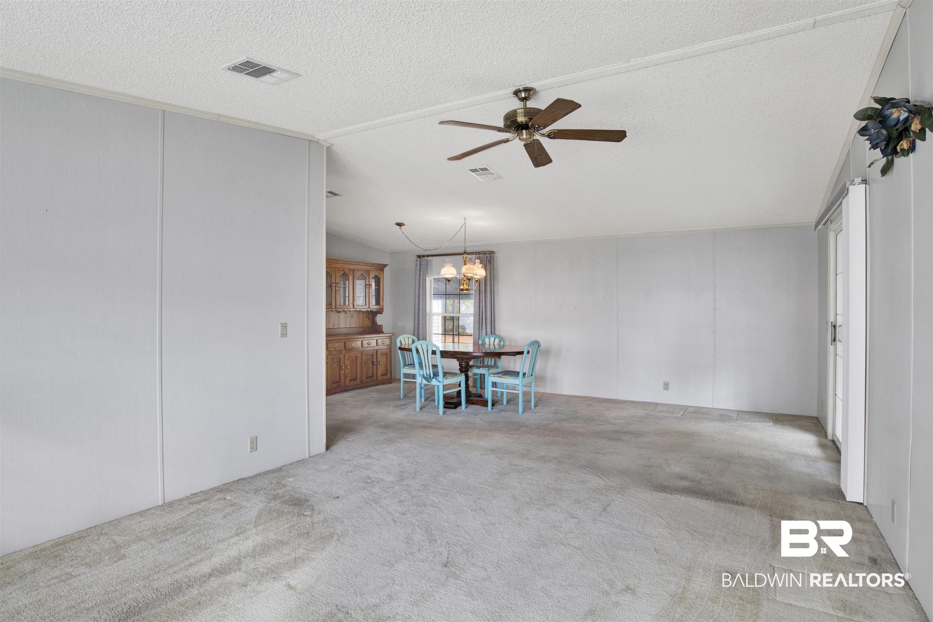 1216 Ridgewood Drive Lillian, AL 36549 - Photo 8 of 29 Dining room with light colored carpet, a textured ceiling, a ceiling fan, a decorative wall, and a chandelier