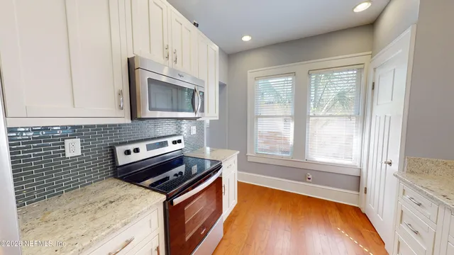 a kitchen with granite countertop a stove a sink and a microwave