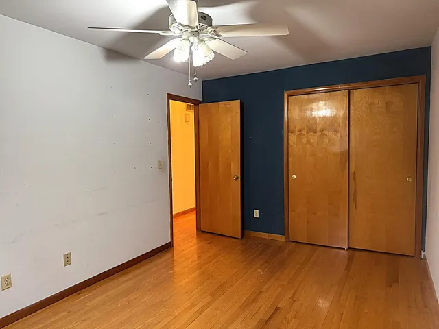 an empty room with wooden floor closet and windows