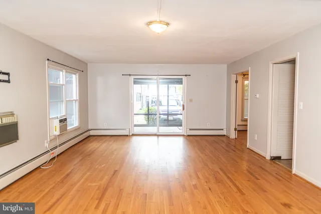 a view of an empty room with wooden floor and a fireplace