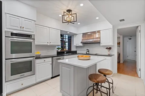 a kitchen with stainless steel appliances granite countertop a sink a stove a refrigerator and island with wooden floor