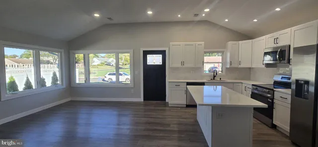 an open kitchen with kitchen island granite countertop a stove top oven a sink and a refrigerator