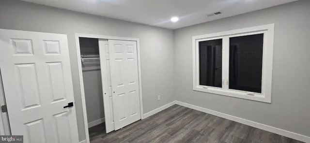 a view of an empty room with wooden floor and closet