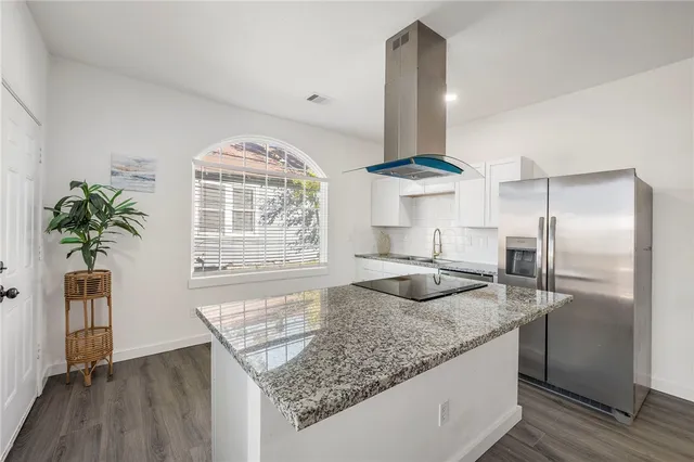 a kitchen with stainless steel appliances granite countertop a sink a stove and a wooden floors