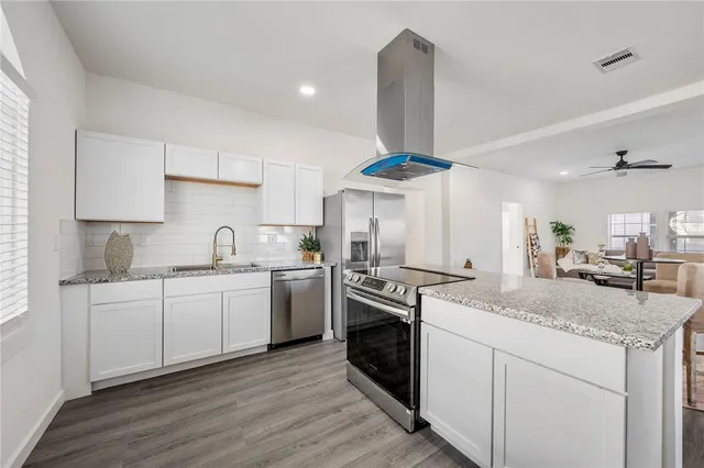 a kitchen with granite countertop a sink stainless steel appliances and cabinets