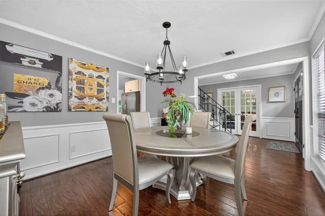 a dining room with wooden floor a chandelier a wooden table and chairs