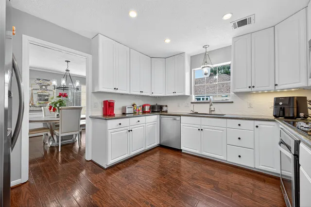 a kitchen with granite countertop stainless steel appliances sink cabinets and wooden floor
