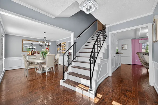 a view of a hallway with wooden floor table and chairs