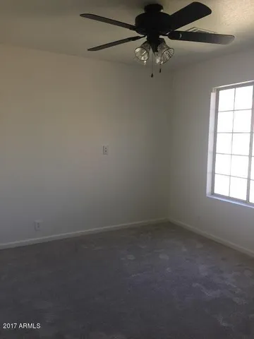 an empty room with a window and a fan