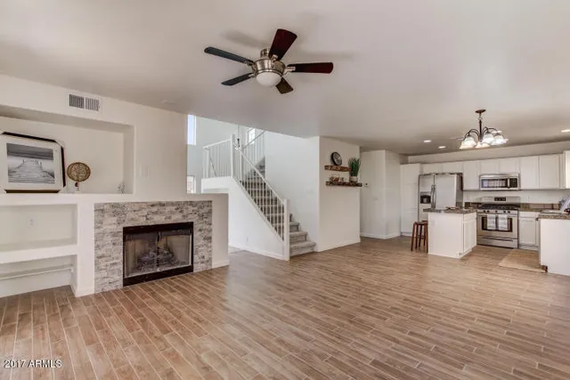 a view of an empty room and kitchen with fireplace wooden floor