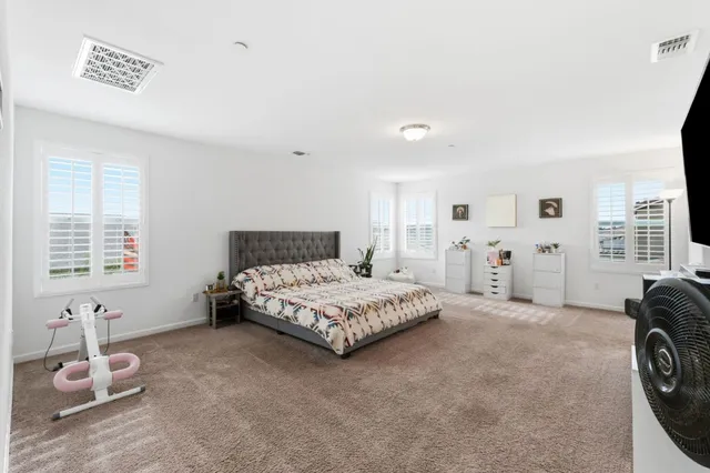 a spacious bedroom with a bed a table and windows