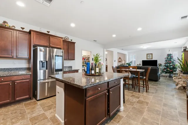 a kitchen with stainless steel appliances granite countertop a table chairs sink refrigerator and microwave