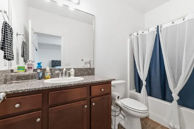 a bathroom with a granite countertop sink toilet and a mirror