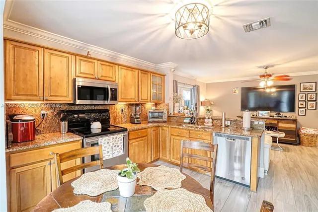 a kitchen with stainless steel appliances wooden floor and a refrigerator